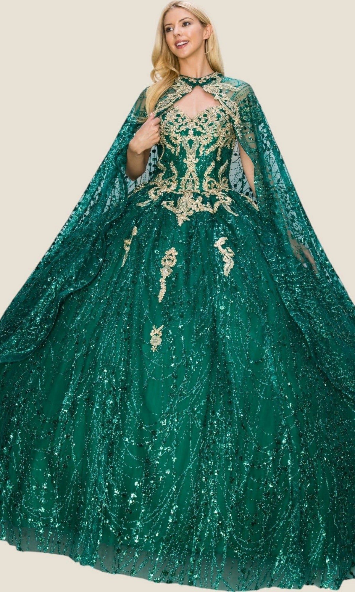 A woman wears the Quinceanera Dress 4201 by Cinderella Couture, a floor-length emerald green ball gown embellished with gold embroidery and sequins, complete with a matching sheer cape.